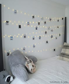 there is a stuffed animal that is on the bed with lights strung up behind it