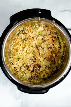 a pot filled with rice and vegetables on top of a stove burner next to a spoon