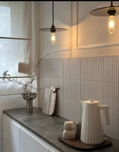 a kitchen counter topped with white vases and lights