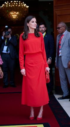 a woman in a red dress standing on a red carpet