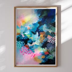 an abstract painting hangs on the wall next to a white wall with a wooden frame