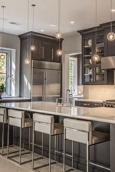 a large kitchen with stainless steel appliances and bar stools in front of the counter