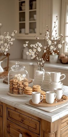 a kitchen counter topped with plates and cups filled with cookies next to a vase full of flowers