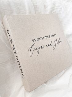 a wedding guest book on a bed with white sheets