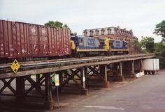 a train traveling over a bridge with lots of cargo containers on it's sides