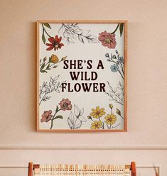 a sign that says she's a wild flower hanging on the wall next to a window