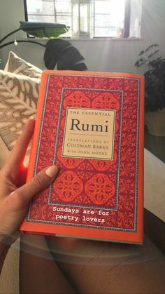 a person holding up an orange book in their hand with the words rumi on it