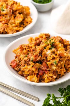 two white plates filled with pasta and meat