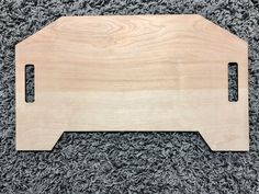 a wooden cutting board sitting on top of a carpeted floor next to a gray rug