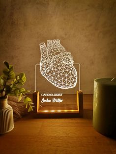 an illuminated heart on a stand next to a potted plant