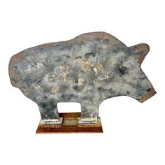 a metal sculpture of a bear on a wooden base with rusted pattered paint