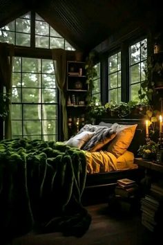 a bedroom with lots of windows, plants and a bed covered in blankets is lit by candles