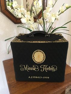 a black box with white flowers in it sitting on a table next to a mirror