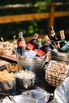 several buckets filled with beer and snacks on a picnic table