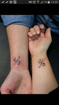 two people holding hands with tattoos on their wrist and one has a small tattoo on the other