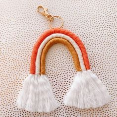 two white and orange tassels hanging from a gold keychain