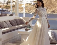 a woman in a wedding dress standing on a porch next to a couch and table