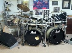 a room filled with lots of musical equipment and pictures on the wall above it's drum set