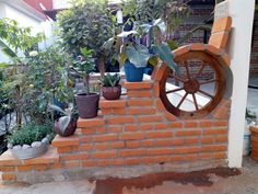 there is a brick wall with plants growing on it and a wheel in the middle