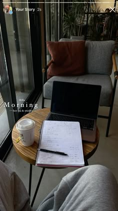 a laptop computer sitting on top of a wooden table next to a cup of coffee