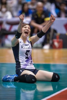 a woman sitting on the floor with her arms in the air