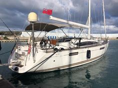 a sailboat docked in the water with a red flag on it's mast