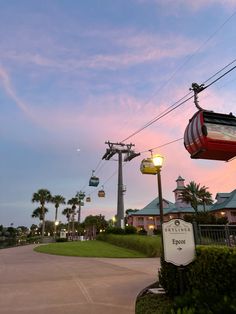 the sky is pink and blue at dusk with palm trees in the foreground, an electric cable car on the right