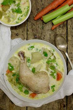 two white bowls filled with soup next to carrots and celery on a wooden table