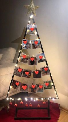 a christmas tree made out of photos and lights with hearts attached to the top, sitting on a red rug