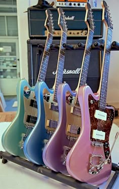 four guitars are lined up on a table