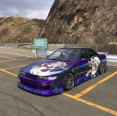 a purple car parked in a parking lot next to a mountain