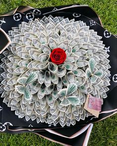 a flower made out of dollar bills sitting on top of a black and white plate