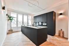 an empty kitchen with black cabinets and white counter tops is seen in this image from the hallway to the living room