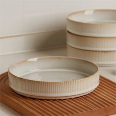 three white dishes sitting on top of a wooden tray