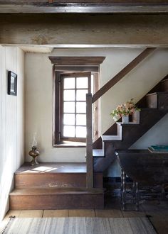 a room with some stairs and a table in it's centerpiece, next to a window