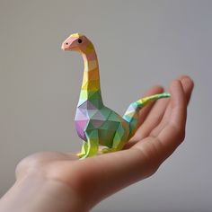 a person's hand holding an origami giraffe