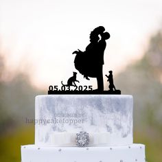 a wedding cake topper with a silhouette of a man and woman holding a dog