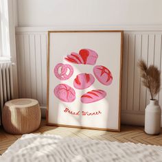 a framed art print on the floor next to a vase with some flowers in it