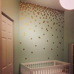 a baby's room decorated with gold polka dot wallpaper and white crib