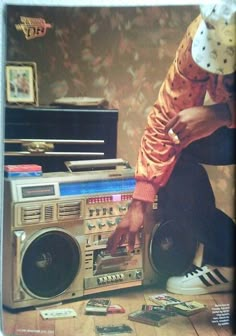 a man sitting on the floor next to an old radio and boombox with his feet propped up against it