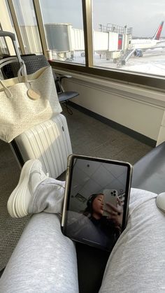 a person sitting on a couch holding an electronic device in their lap while looking out the window