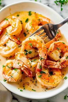 a white bowl filled with cooked shrimp and garnished with parsley