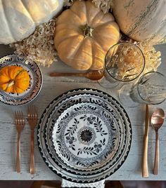 the table is set with silverware and pumpkins