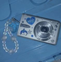 a silver camera sitting on top of a blue table next to a necklace and bracelet