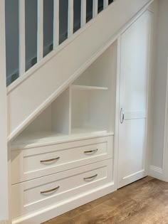 an empty room with white drawers under the stairs