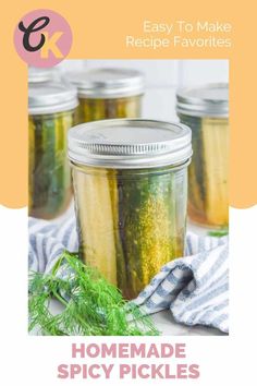 four jars filled with pickles sitting on top of a counter next to a blue and white towel