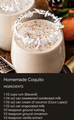 two glasses filled with homemade coquito ingredients on top of a wooden table next to pine cones