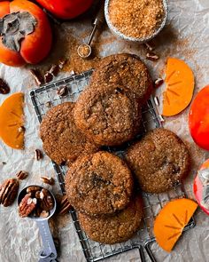 several cookies are on a cooling rack with some fruit and nuts around them, along with other food items