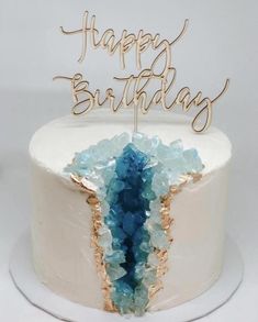 a white cake with blue and gold frosting that says happy birthday on top of it