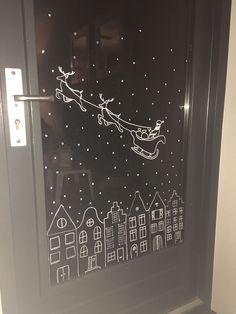 a glass door decorated with santa's sleigh flying through the night sky